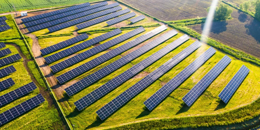 Solar panels and wind turbines under a bright sky representing renewable energy.